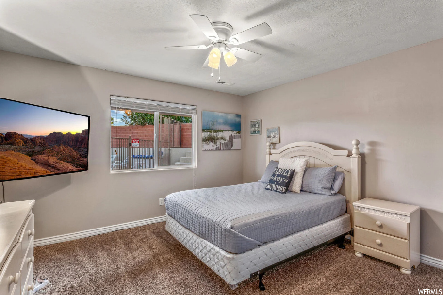 Bedroom featuring dark carpet, ceiling fan, and a textured ceiling