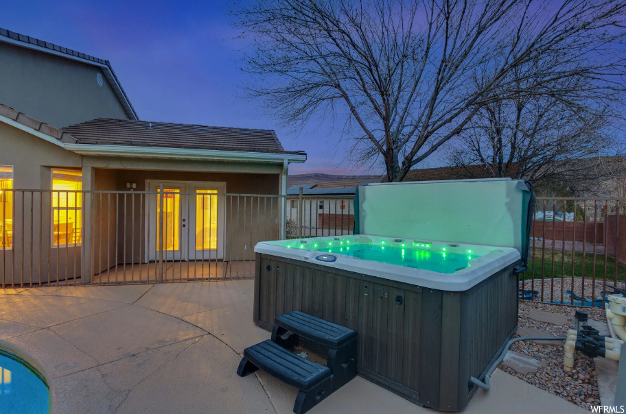 Patio terrace at dusk featuring a hot tub