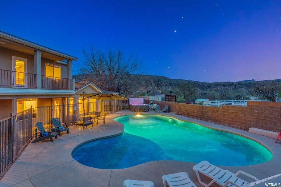 Pool at dusk with a patio and a mountain view