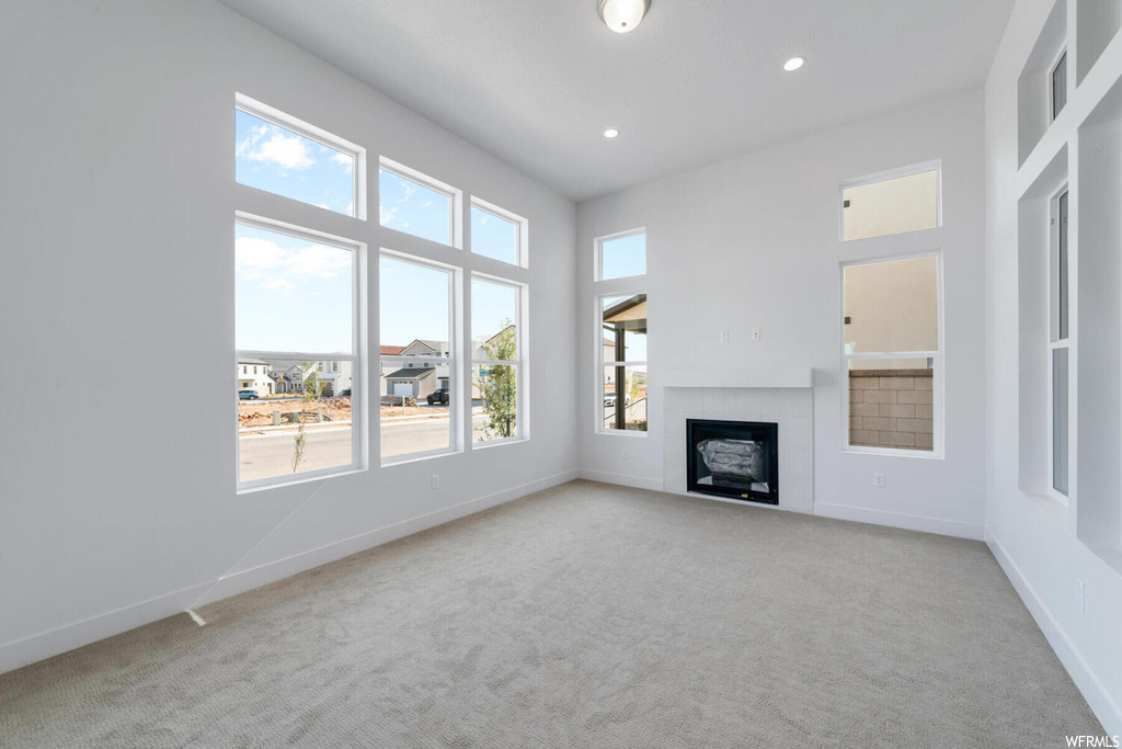 Unfurnished living room featuring light colored carpet and plenty of natural light