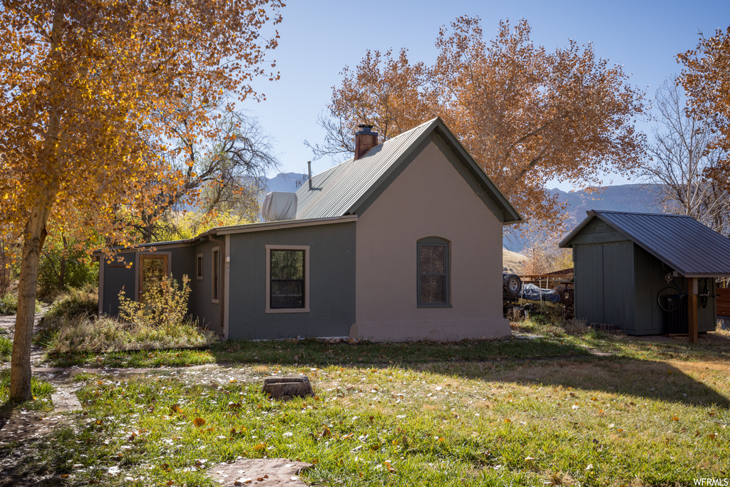 Rear view of property featuring a lawn and a storage shed