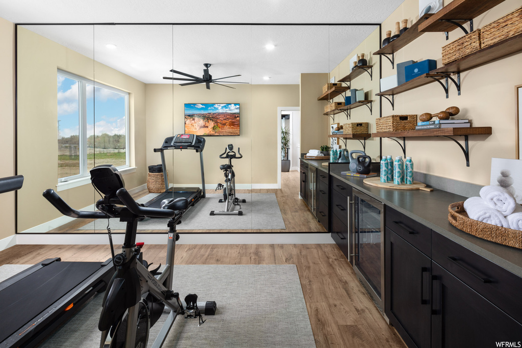 Workout room with light hardwood / wood-style flooring, ceiling fan, and beverage cooler