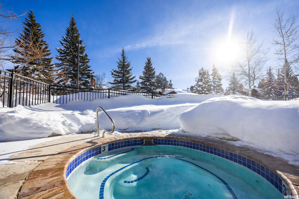 Snow covered pool featuring an in ground hot tub