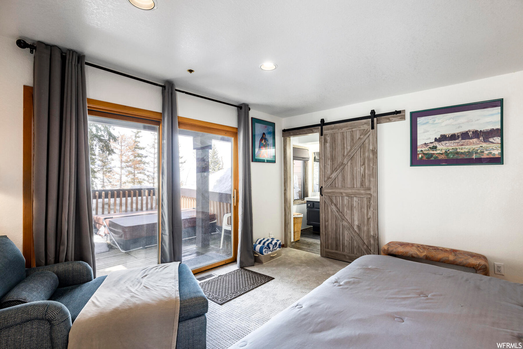 Carpeted bedroom with ensuite bath, a barn door, and access to exterior