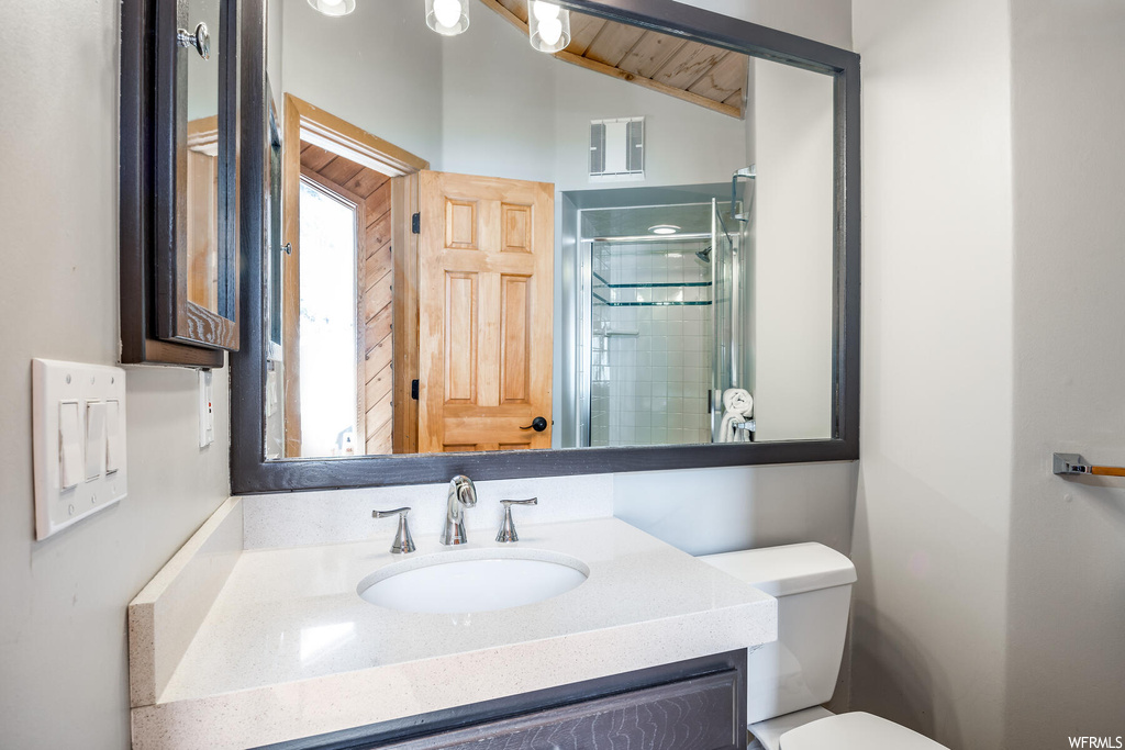 Bathroom featuring wood ceiling, toilet, vanity with extensive cabinet space, and vaulted ceiling