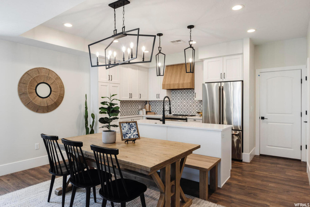 Dining space featuring dark hardwood / wood-style flooring, sink, and a notable chandelier
