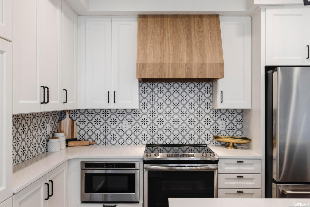 Kitchen featuring tasteful backsplash, white cabinetry, and appliances with stainless steel finishes