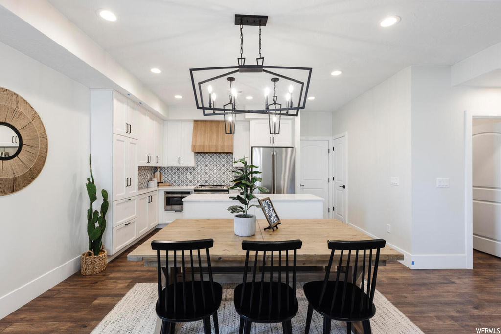 Dining space with dark hardwood / wood-style flooring and an inviting chandelier