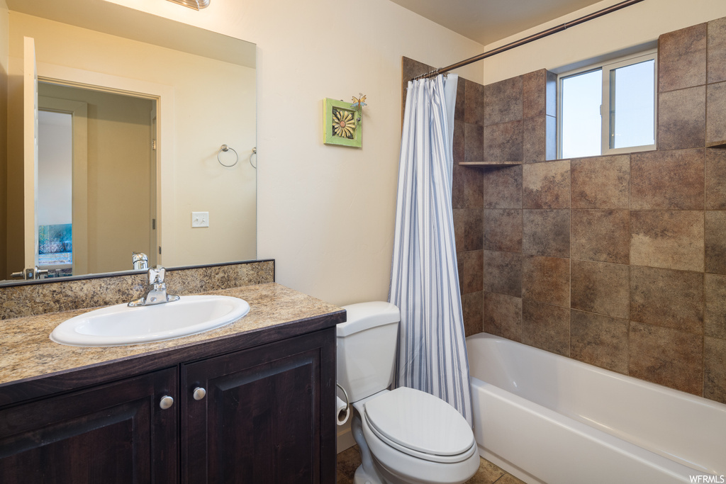 Full bathroom featuring shower / bathtub combination with curtain, toilet, and vanity