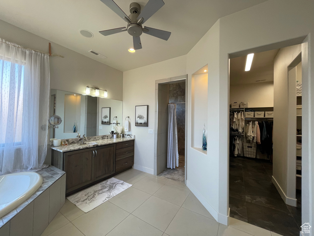 Bathroom featuring tile flooring, oversized vanity, ceiling fan, and tiled tub