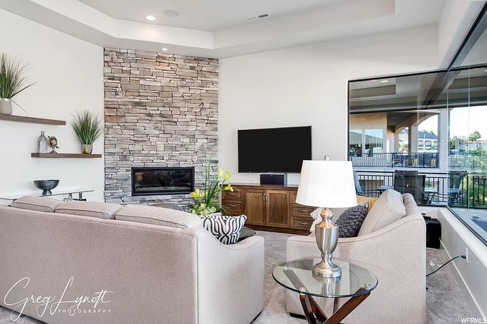 Living room featuring a stone fireplace and a raised ceiling