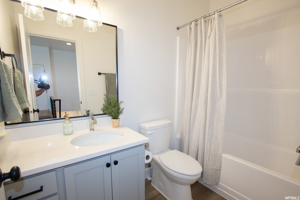 Full bathroom featuring toilet, shower / tub combo, oversized vanity, and hardwood / wood-style flooring