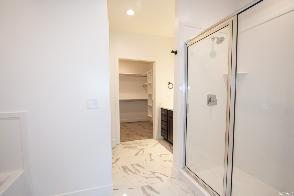 Bathroom with tile flooring, walk in shower, and vanity