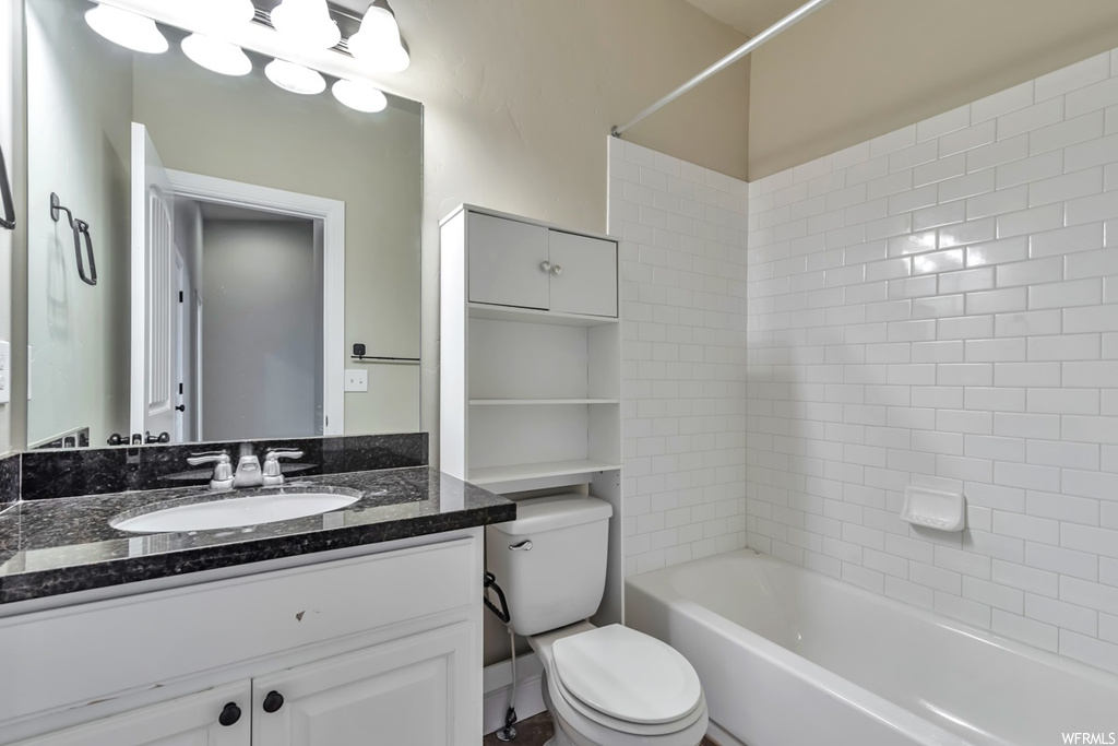 Full bathroom with tiled shower / bath combo, toilet, and vanity with extensive cabinet space