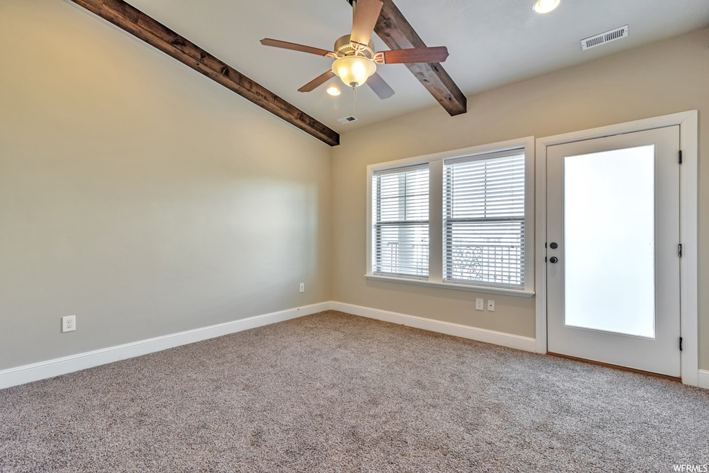 Empty room featuring ceiling fan, beam ceiling, and light carpet