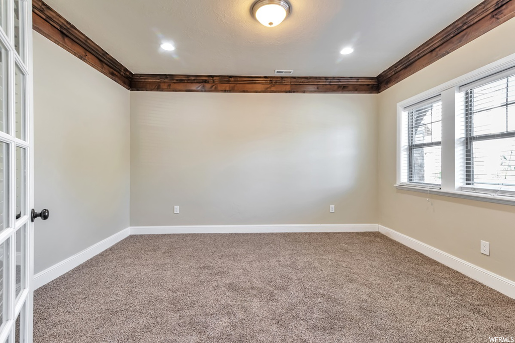 Empty room featuring ornamental molding, light carpet, and french doors