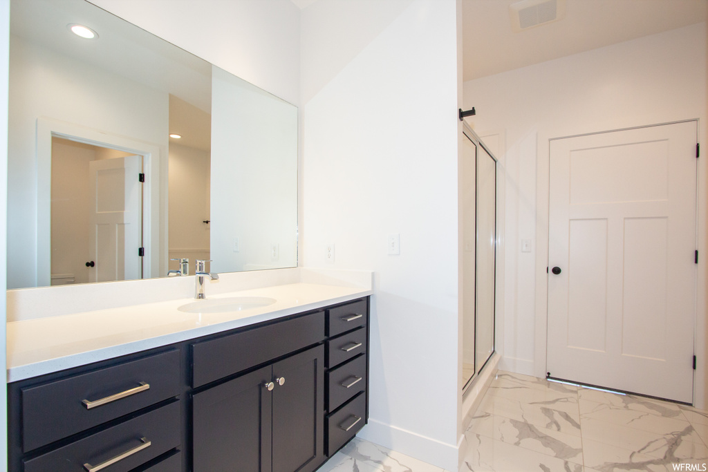 Bathroom with vanity, a shower with shower door, and tile flooring