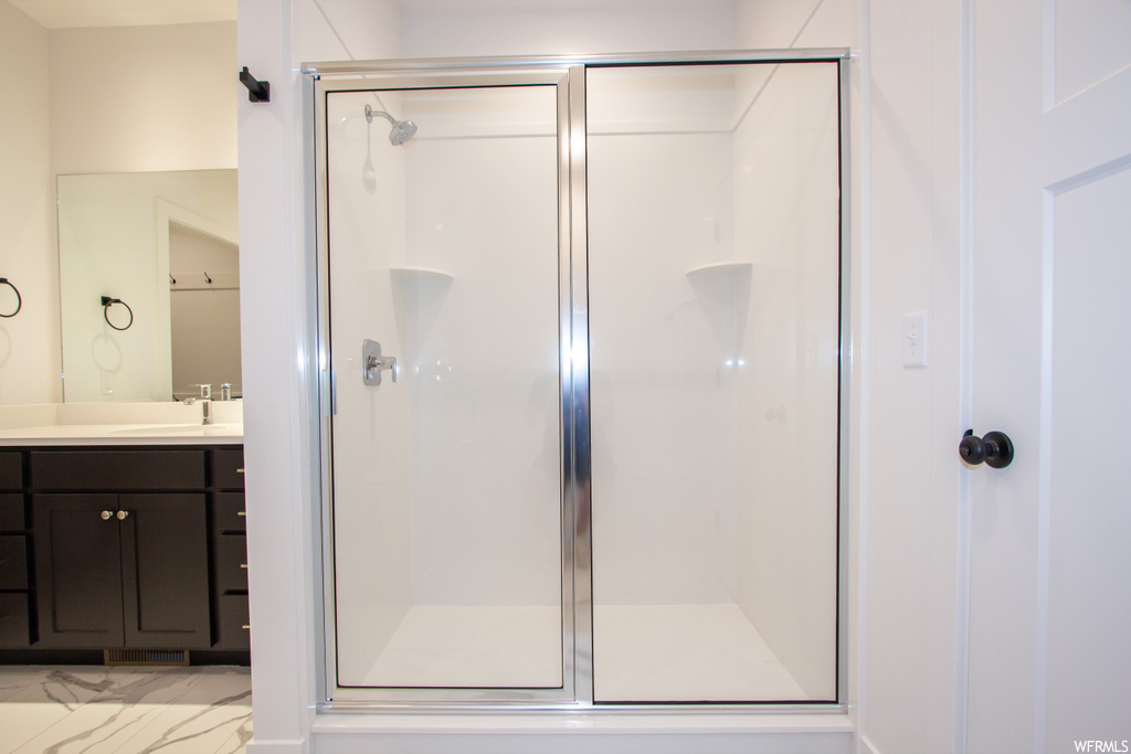 Bathroom featuring vanity, a shower with door, and tile flooring
