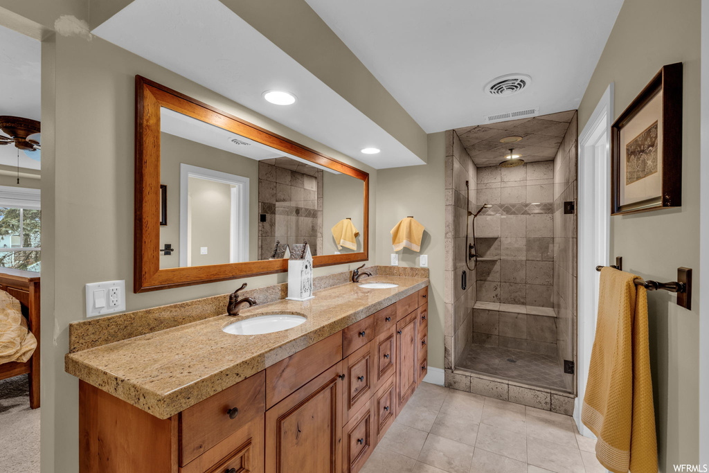 Bathroom featuring oversized vanity, a shower with shower door, double sink, and tile flooring