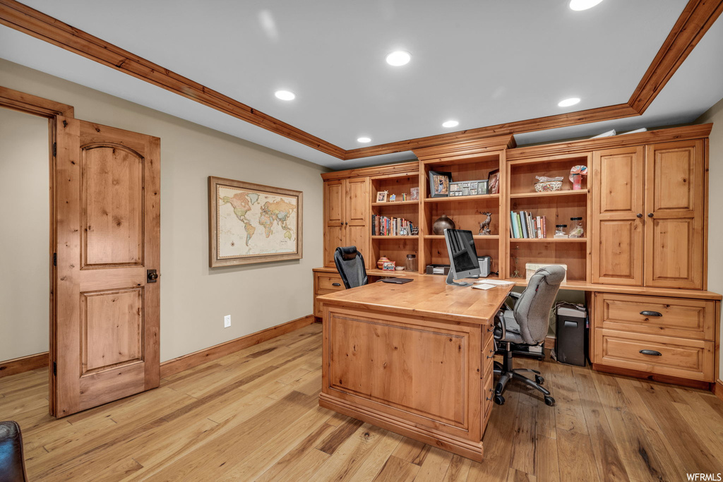 Office with light hardwood / wood-style flooring and crown molding