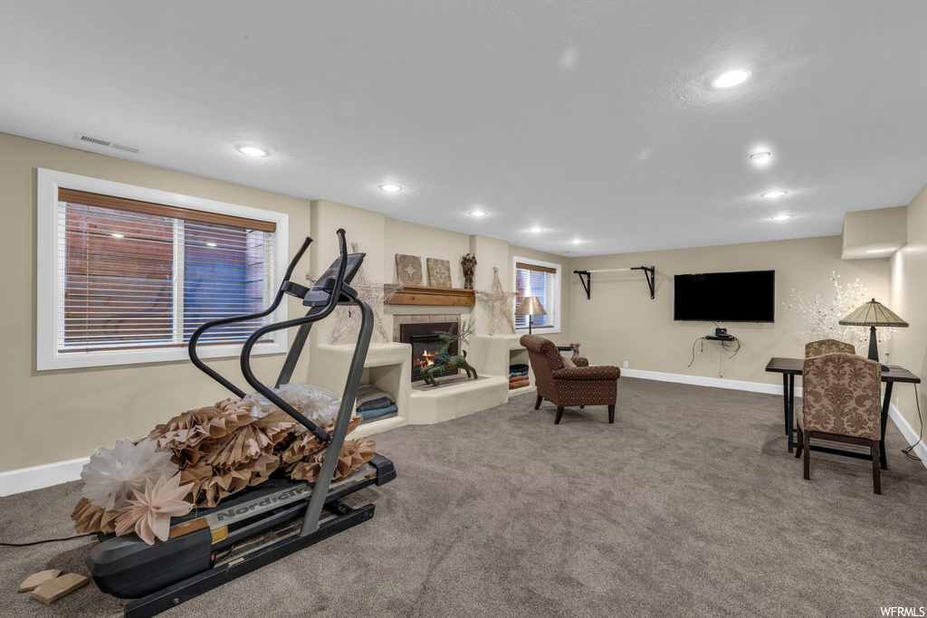 Workout area featuring a tiled fireplace and carpet