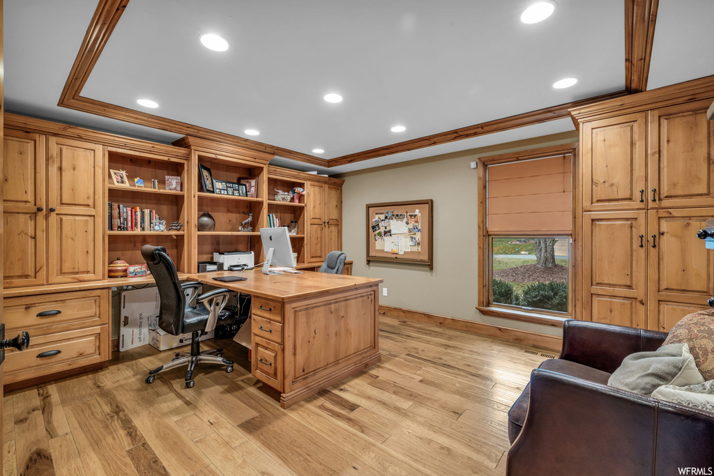 Office with light hardwood / wood-style flooring and ornamental molding
