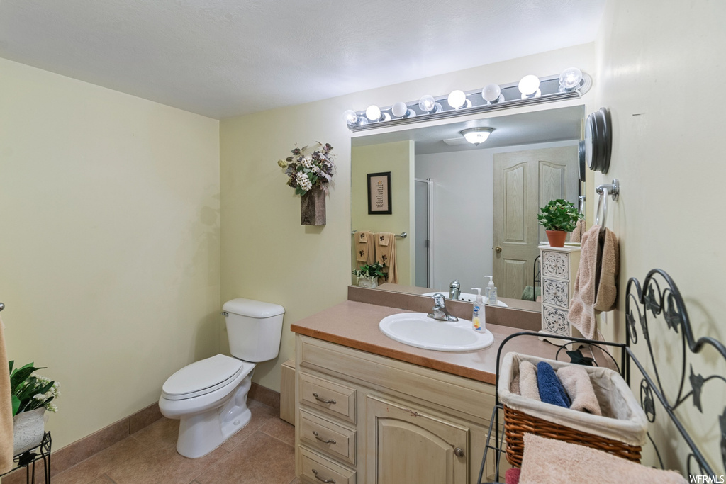 Bathroom with toilet, tile floors, and vanity with extensive cabinet space