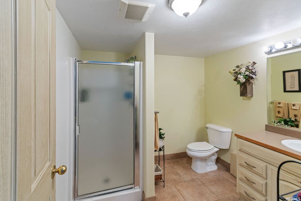 Bathroom featuring toilet, an enclosed shower, tile floors, and vanity