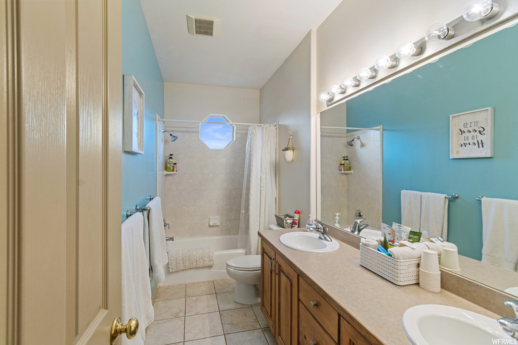 Full bathroom with toilet, tile floors, shower / bath combo, and double vanity