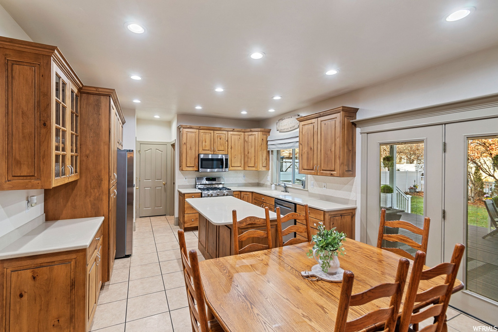 Kitchen with sink, light tile flooring, stainless steel appliances, a kitchen island, and backsplash