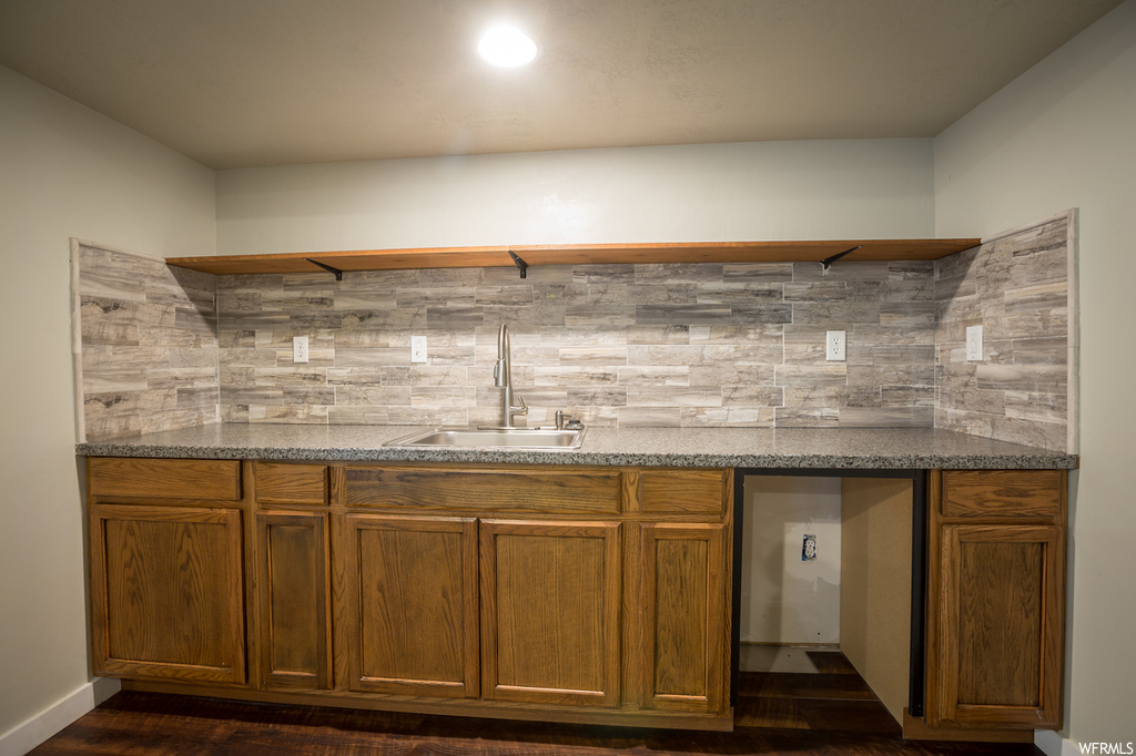 Kitchen with dark hardwood / wood-style flooring, tasteful backsplash, sink, and light stone counters