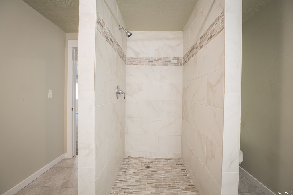 Bathroom featuring a textured ceiling and a tile shower
