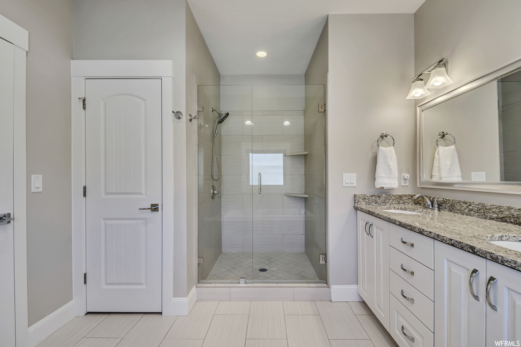 Bathroom featuring double vanity, a shower with shower door, and tile flooring