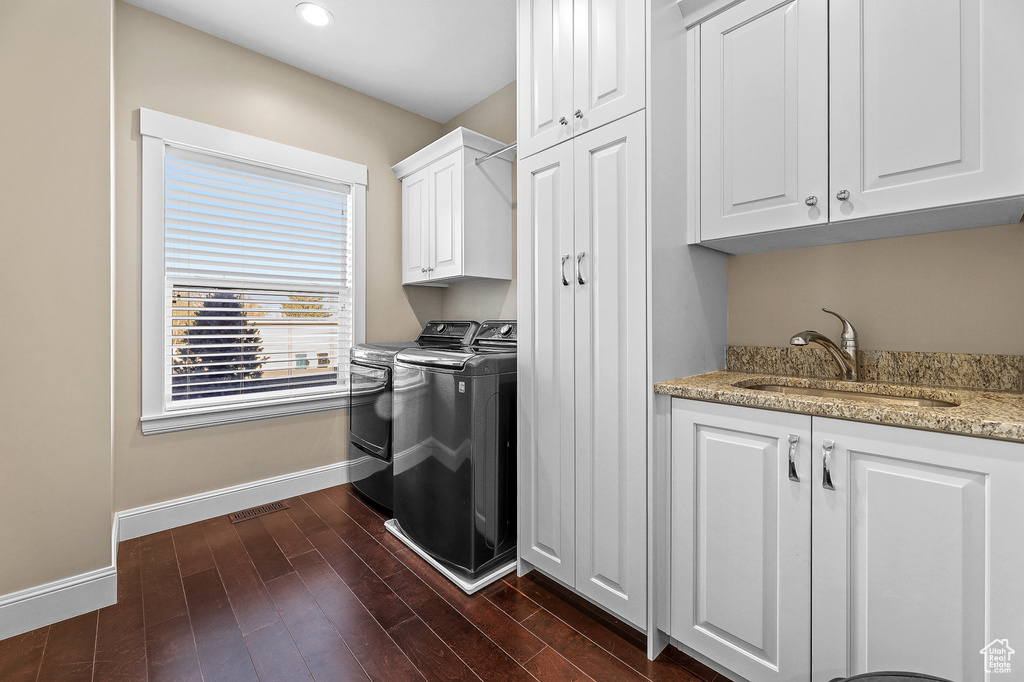 Laundry area featuring cabinets, sink, dark hardwood / wood-style flooring, and washing machine and clothes dryer