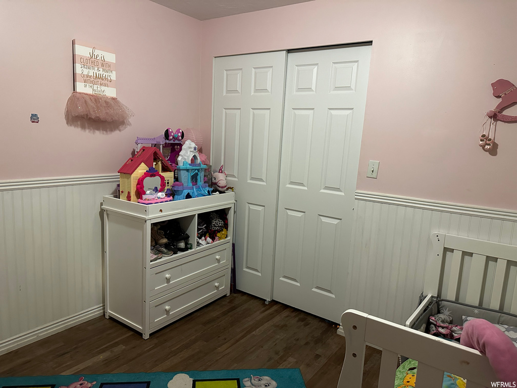 Bedroom with dark hardwood / wood-style flooring, a closet, and a nursery area
