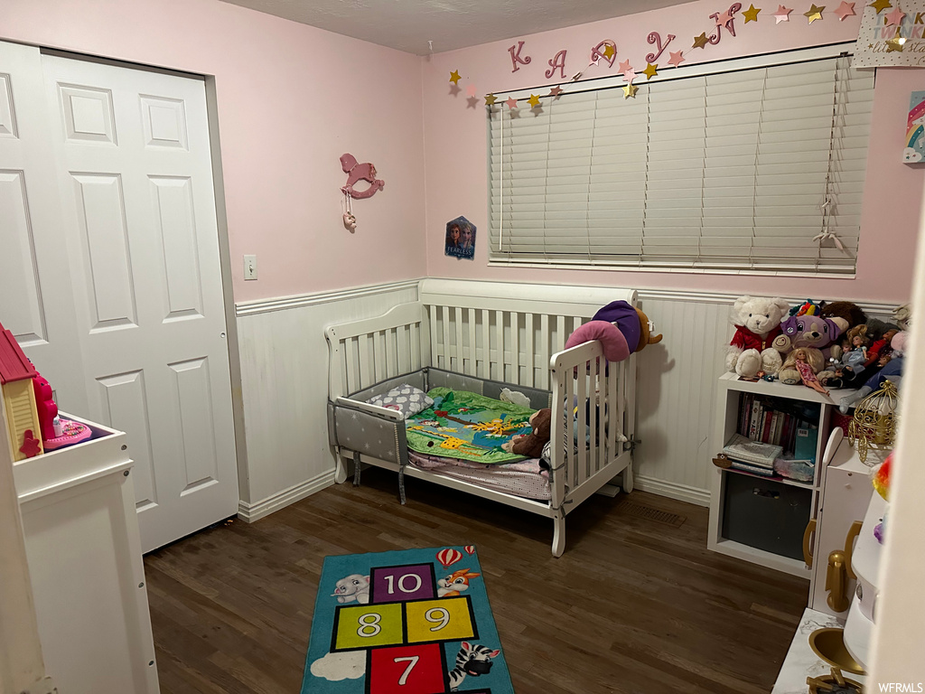 Bedroom featuring dark hardwood / wood-style floors and a nursery area