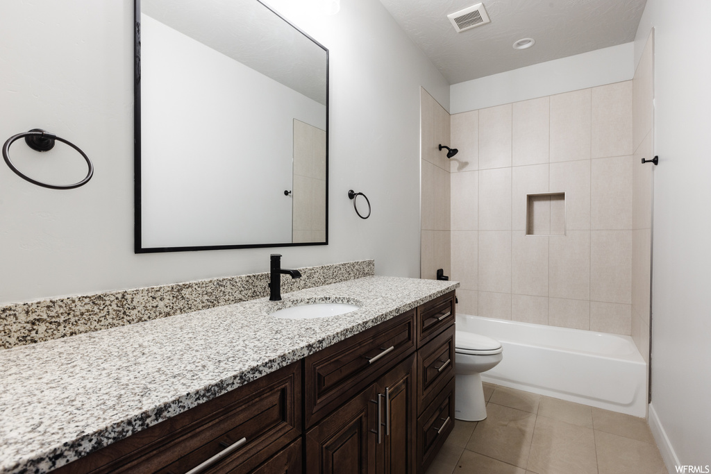 Full bathroom featuring tile flooring, tiled shower / bath combo, toilet, and vanity with extensive cabinet space