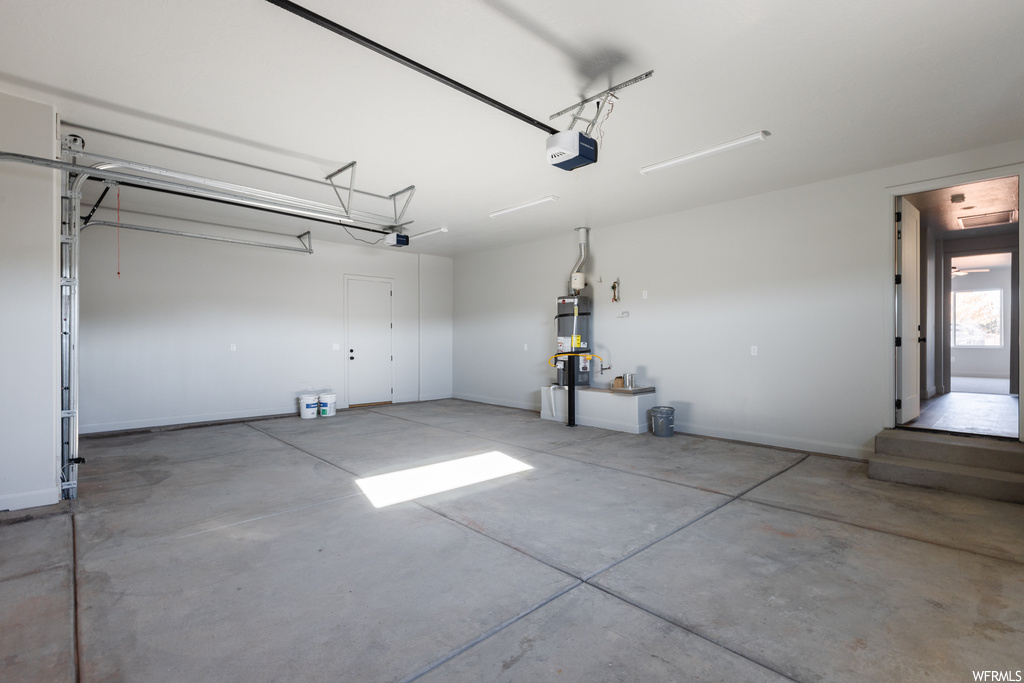 Garage with a garage door opener and strapped water heater