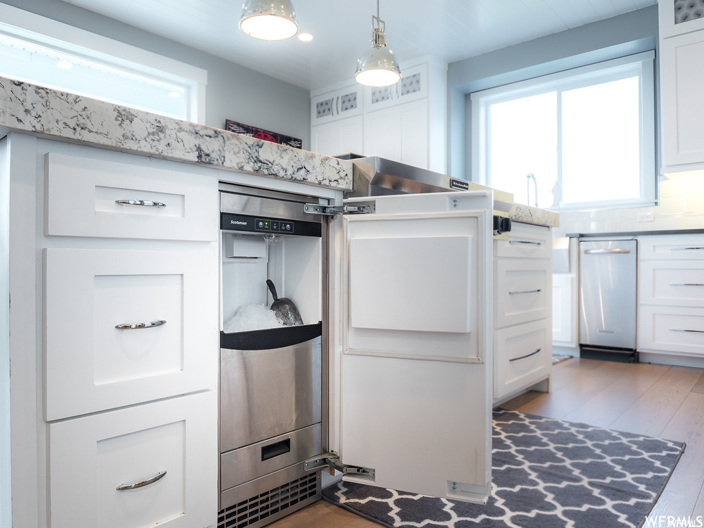 Kitchen with white cabinets, tasteful backsplash, decorative light fixtures, and hardwood / wood-style floors