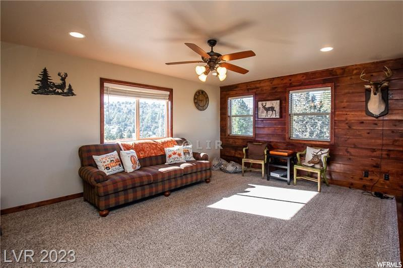 Living room featuring wooden walls, ceiling fan, and carpet floors