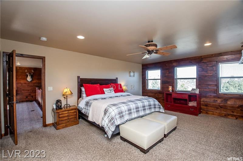 Carpeted bedroom featuring wood walls and ceiling fan