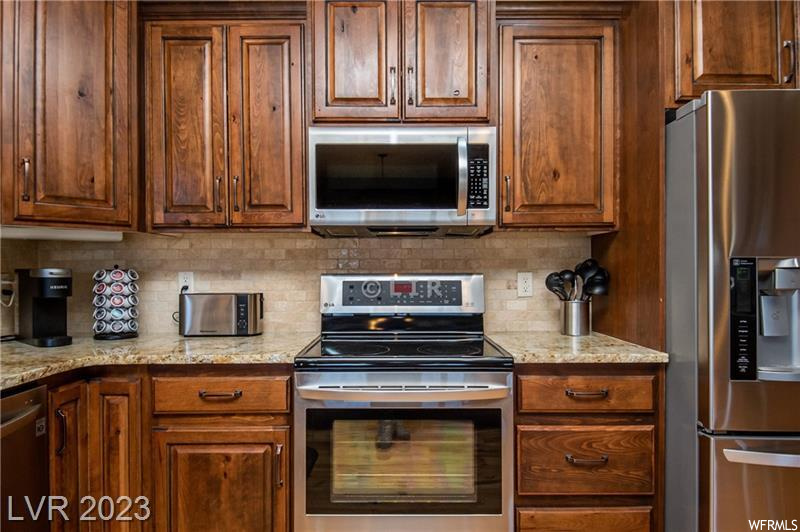Kitchen featuring light stone counters, tasteful backsplash, and stainless steel appliances