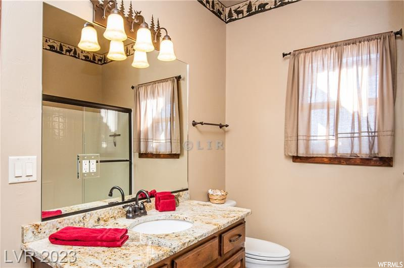 Bathroom featuring toilet, a notable chandelier, plenty of natural light, and vanity
