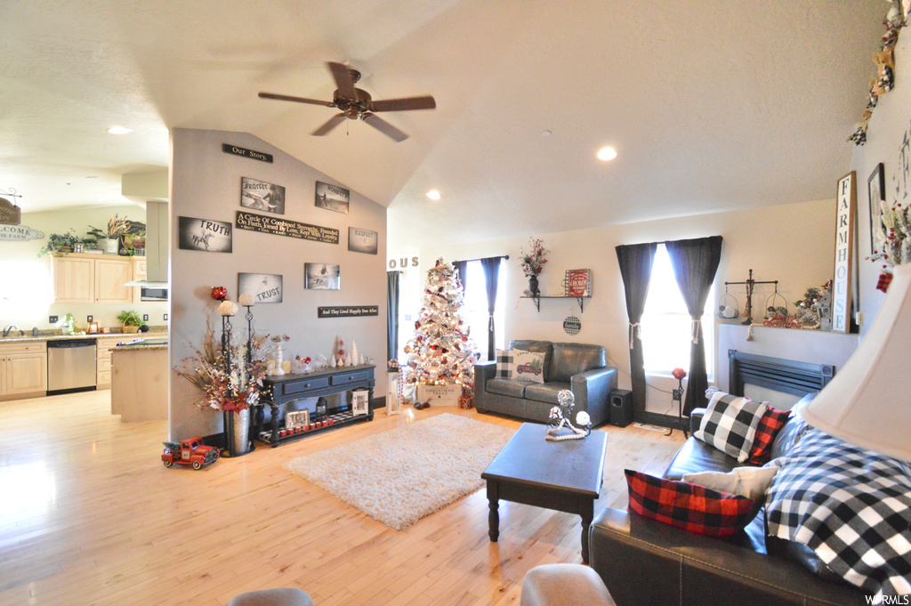 Living room with lofted ceiling, ceiling fan, and light hardwood / wood-style floors