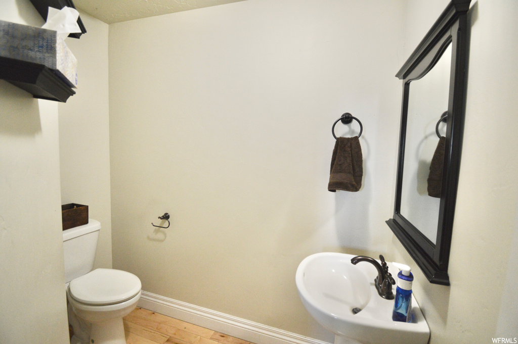 Bathroom with toilet, hardwood / wood-style floors, and sink