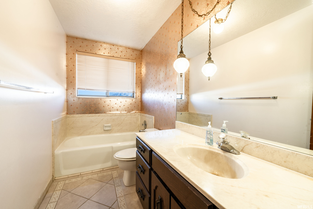 Bathroom featuring toilet, tile floors, a washtub, and vanity with extensive cabinet space