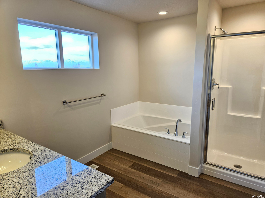 Bathroom featuring separate shower and tub, hardwood / wood-style flooring, and vanity