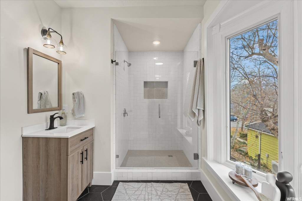 Bathroom with a wealth of natural light, tile floors, and a shower with shower door