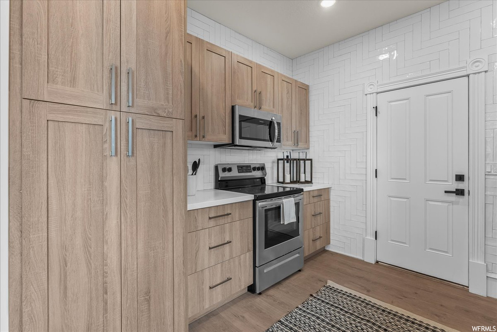 Kitchen with tasteful backsplash, stainless steel appliances, and light hardwood / wood-style floors
