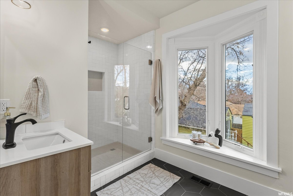 Bathroom with vanity, a wealth of natural light, tile floors, and an enclosed shower